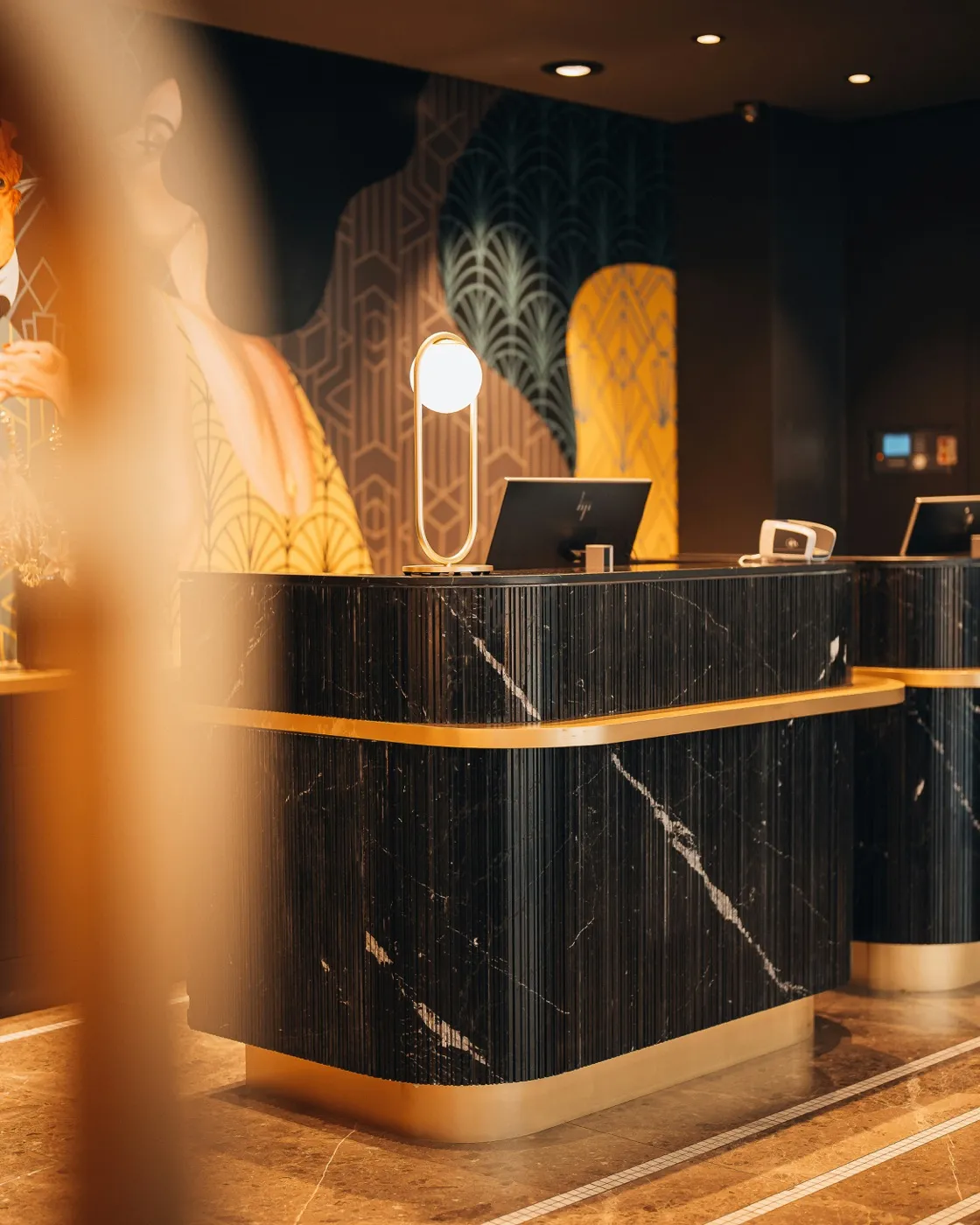 An art-deco hotel front desk with black marble and gold trim — the kind of feature that makes a condo a condotel